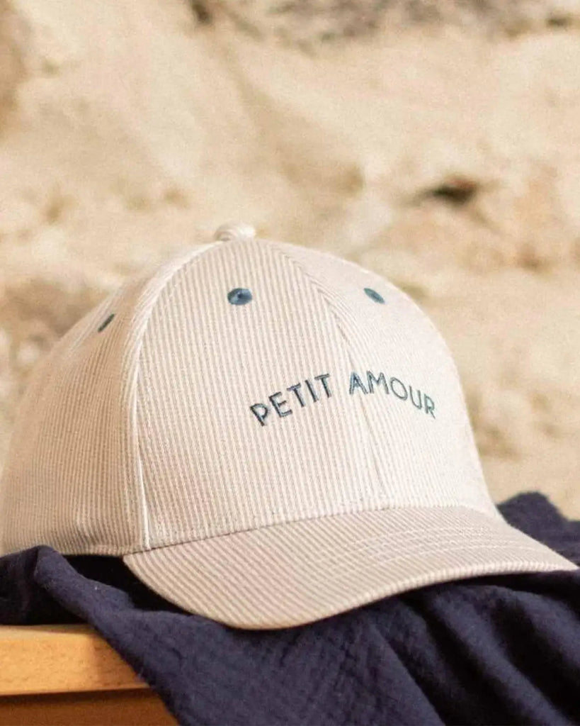 Casquette pour bébé à rayures beige et à broderie "Petit amour" bleue de la marque Bobine Paris.