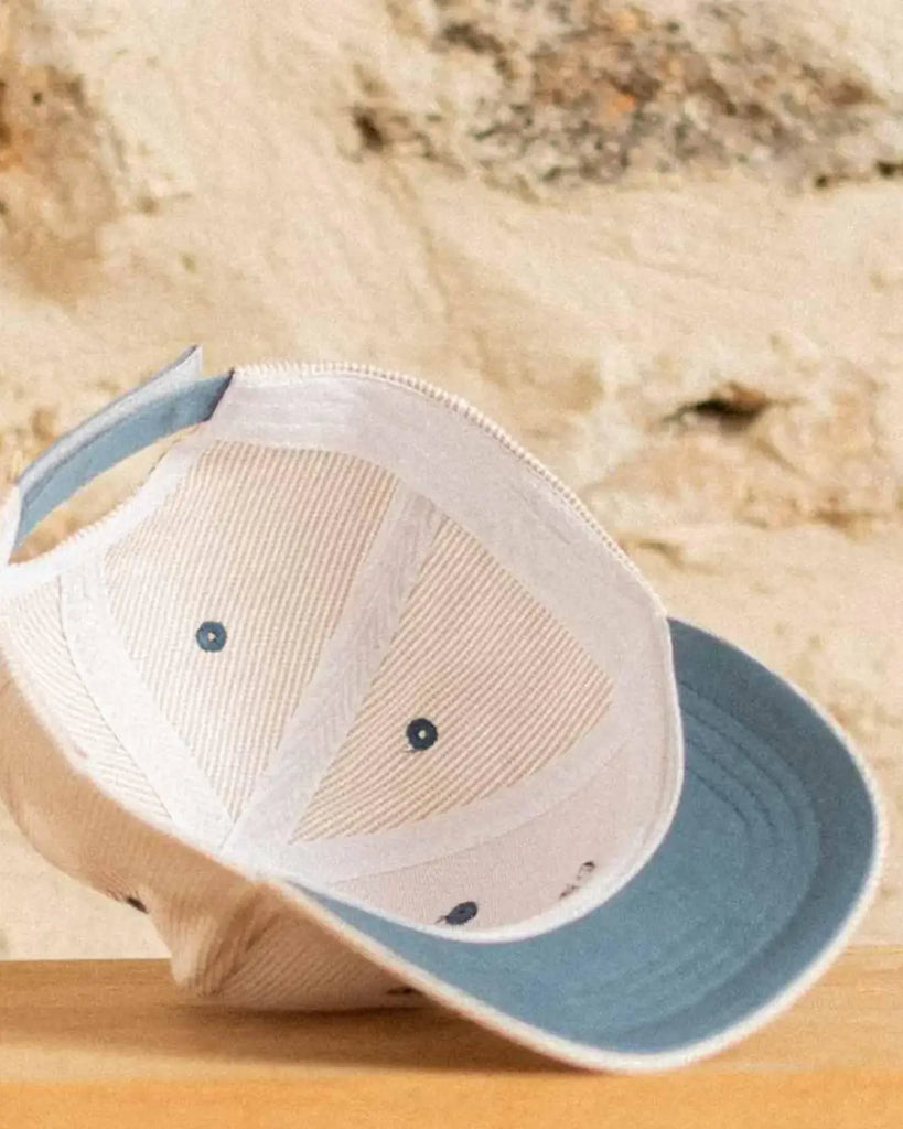 Vue de l'intérieur de la casquette pour bébé à rayures beige et à broderie "Petit amour" bleue de la marque Bobine Paris.