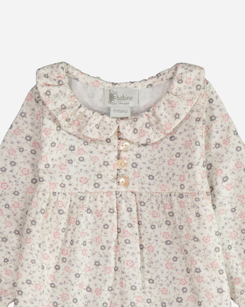 Zoom sur le col claudine de la blouse fleurie rose et gris.