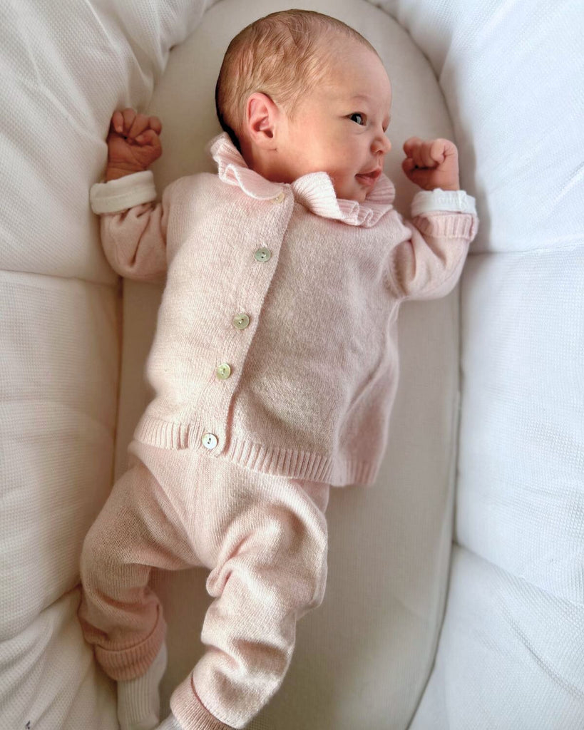 Bébé allongé portant un ensemble (un cardigan rose et un pantalon rose assorti).