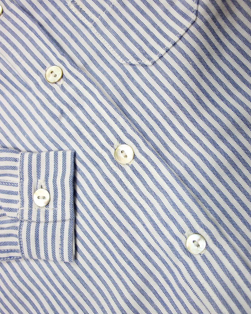 Zoom sur les boutons de la chemise à rayures blanches et bleues.